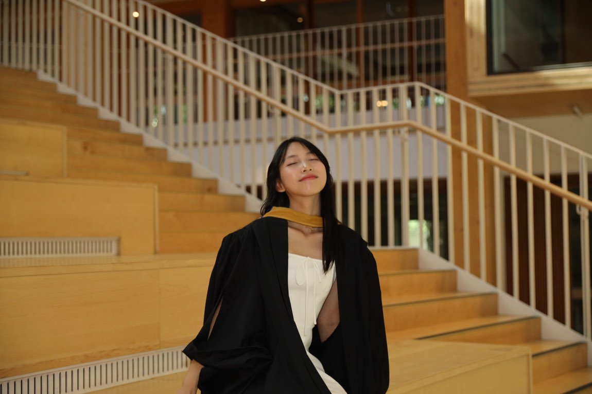 Graduate resting peacefully on warm timber stairs