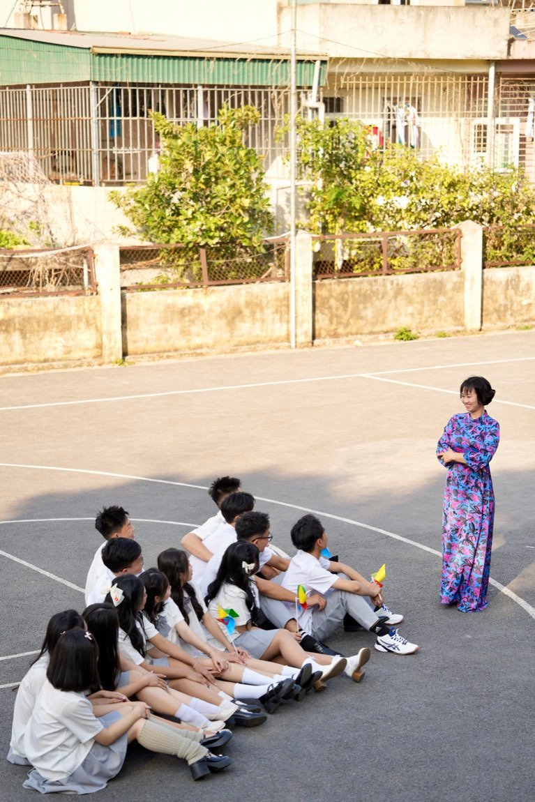 Teacher standing before her seated class against the old school wall