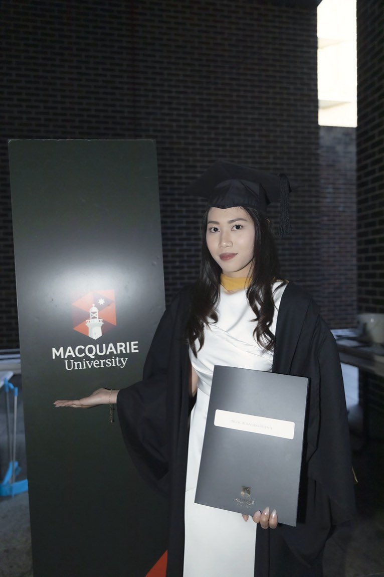Graduate presenting her testamur under the university sign
